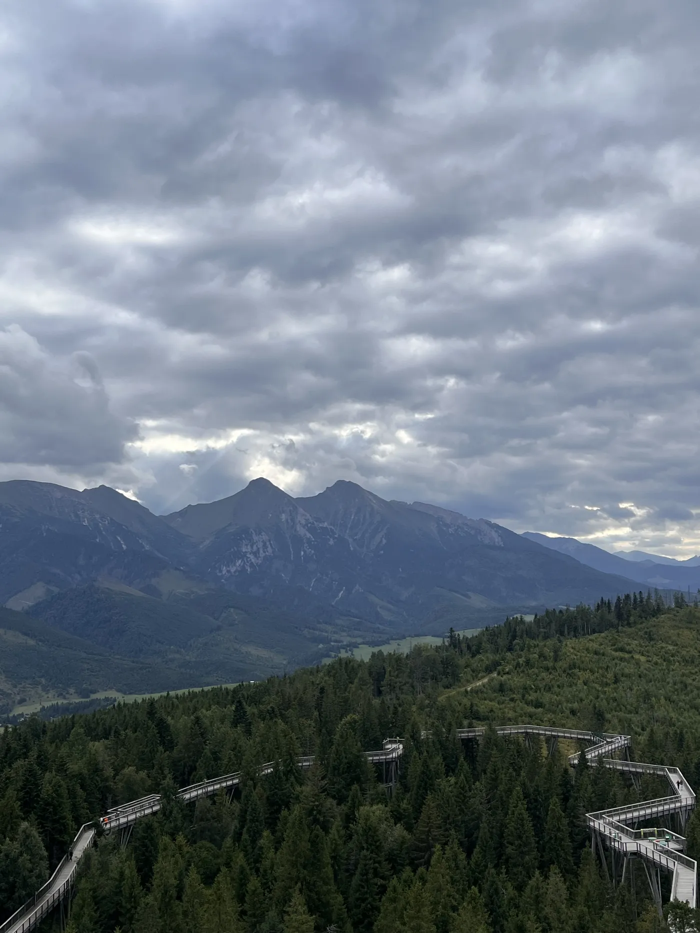 Clouds over the Tatra mountains and a wooden treetop walkway through pine forest